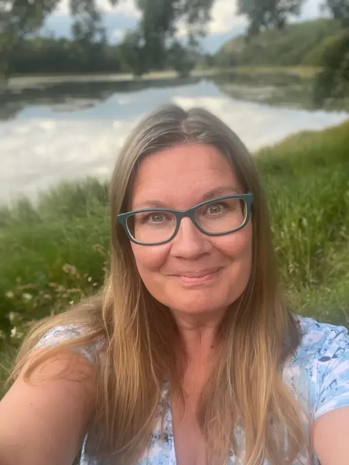 Ellinor Wikman i glasögon vid en sjö en sommardag.